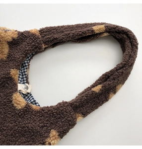 Close-up of brown plush shoulder bag with polka dots, blue checkered lining and snap