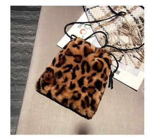 Detail shot of leopard print faux fur bucket bag with drawstring on a textured surface