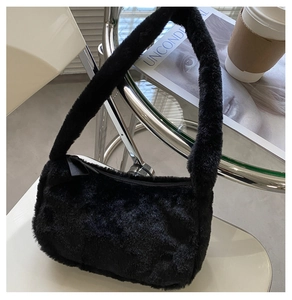 Detail of black faux fur shoulder bag with soft plush texture on a stylish white chair