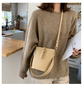 Minimalist cream white bucket bag detail showing smooth leather texture and strap buckles