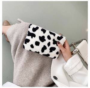 Gros plan d'une trousse à maquillage en peluche à motif vache avec fermeture éclair argentée
