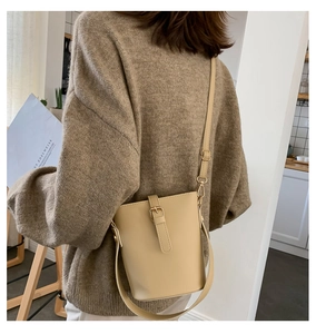 Side view of cream leather bucket bag with adjustable strap on model for stylish commute