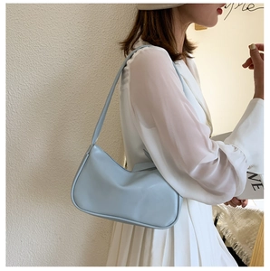 Fashionable light blue half-moon shoulder bag styled with a white outfit and minimal aesthetic