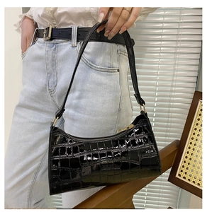 Close-up of black crocodile pattern faux leather shoulder bag with gold zipper and texture