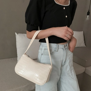 Sac baguette chic blanc crème à motif crocodile porté par un mannequin en tenue décontractée