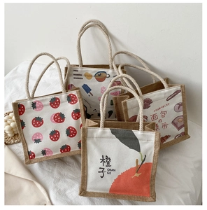 Detail view of four canvas tote bags with fruit and bakery prints and jute sides