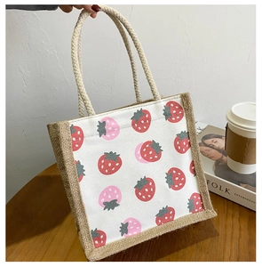 Detailed close-up of a canvas tote bag with strawberry print and natural jute sides