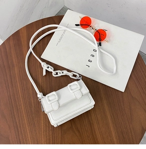 Detailed shot of white mini crossbody bag with resin chain on a wooden table