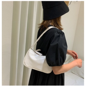 Minimalist white hobo shoulder bag styled with a black dress and a matching sun hat