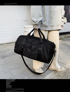 Détail du sac de voyage en nylon noir avec poignées renforcées et une bandoulière robuste
