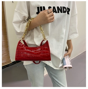 Close-up of red crocodile pattern patent leather shoulder bag with gold chain strap