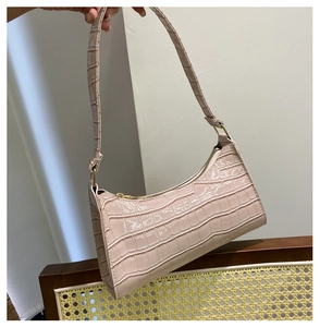 Close-up of pink faux crocodile leather shoulder bag with gold zipper and sleek strap