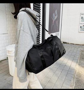 Sac de voyage noir grande capacité avec bandoulière et poche latérale porté par un mannequin