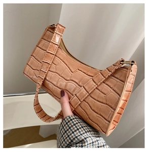 Detail view of a vintage brown crocodile pattern underarm bag with adjustable strap