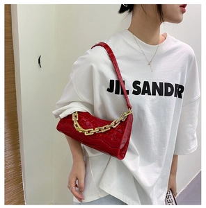 Detail of red crocodile pattern shoulder bag featuring a chunky gold chain strap