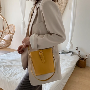 Minimalist yellow leather bucket bag with top handle and adjustable shoulder strap