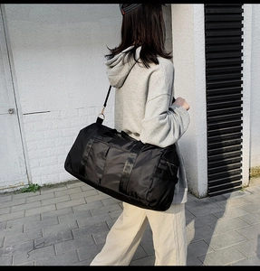 Vue latérale du grand sac de voyage noir avec bandoulière réglable et sangles tissées
