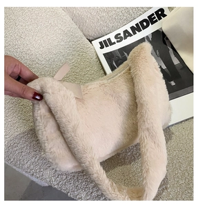 Detail of a beige faux fur shoulder bag with a plush texture and leather bow decoration