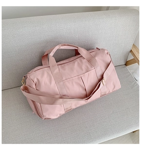 Sac de voyage rose grande capacité avec séparation sec-humide sur un canapé gris