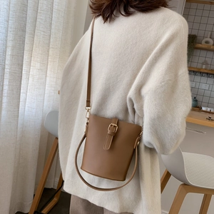 Minimalist coffee brown leather bucket bag with adjustable strap shown on a model