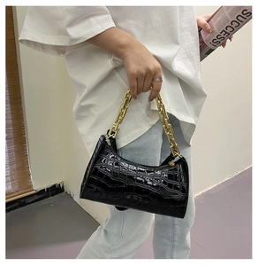 Detail of black crocodile texture underarm bag with thick gold chain link handle