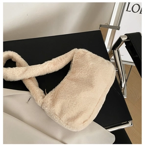 Close-up of fluffy cream-colored plush shoulder bag on a black leather chair in a modern room
