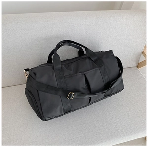 Vue détaillée du sac de voyage noir avec ferrures dorées sur un canapé gris