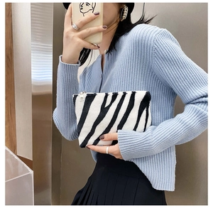 Détail d'une pochette en peluche douce à motif zèbre noir et blanc avec fermeture éclair en métal