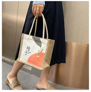 Detail of jute and canvas tote bag featuring orange print and braided rope handles