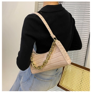 Detail of light pink faux crocodile texture handbag with gold chain strap and zipper