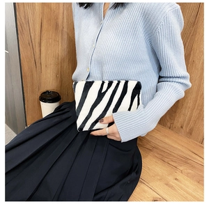 Gros plan d'une pochette à maquillage en peluche motif zèbre tenue par un mannequin