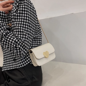 White heart lock mini crossbody bag with gold chain strap shown on model side view