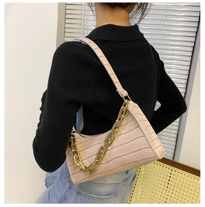 Pink crocodile pattern shoulder bag with a gold chain strap shown on a model's shoulder