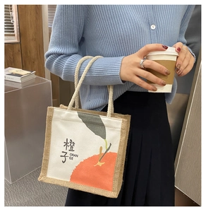 Detail of mini canvas and jute tote bag featuring hand-drawn orange print and rope handles