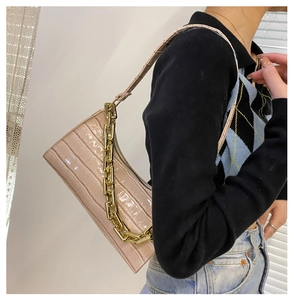 Crocodile embossed light pink underarm bag featuring a chunky gold chain and slim strap