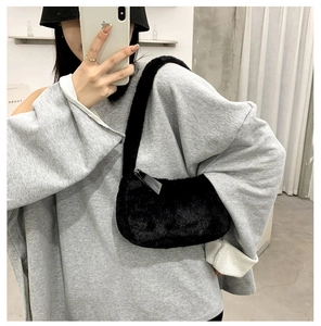 Detail of black faux fur shoulder bag featuring smooth zipper and plush texture on the model