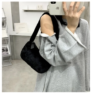 Detail showing the fluffy texture and soft faux fur material of the black plush underarm bag