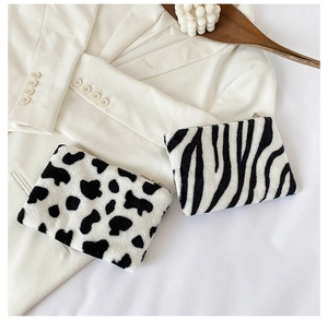 Détail de mini sacs en peluche à motif zèbre et vache avec fermeture éclair sur une veste