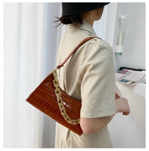 Detailed side view of brown crocodile texture bag with decorative thick gold chain