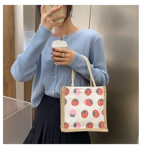 Detail of strawberry print canvas tote bag with rustic jute trim and woven handles
