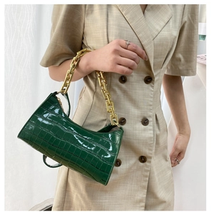 Detail of dark green crocodile pattern underarm bag with thick gold chain handle