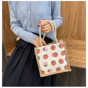Detail of small canvas tote bag with red strawberry print and rustic hemp rope handles