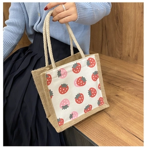 Detailed view of burlap tote bag featuring strawberry print canvas and woven rope handles