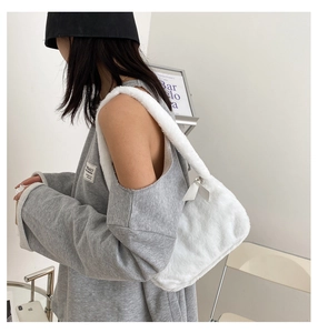 Detail of white faux fur shoulder bag with plush strap and elegant ribbon zip puller