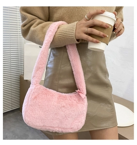 Close-up of pink faux fur shoulder bag worn by a model in a cozy autumn setting