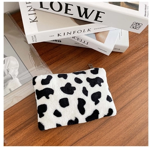 Gros plan d'un porte-monnaie en peluche à motif vache avec fermeture éclair argentée