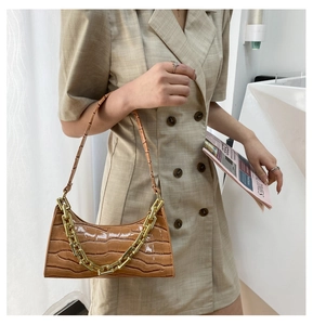 Detailed view of brown crocodile texture leather baguette bag with golden chunky chain