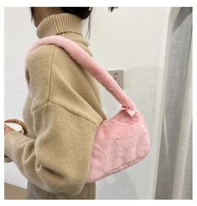 Detail of pink faux fur shoulder bag with satin bow and wide plush strap on a model