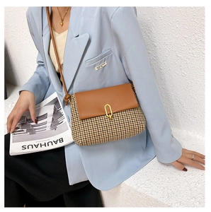 Detail of vintage plaid crossbody bag featuring brown leather flap and houndstooth pattern