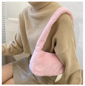 Pink fluffy faux fur baguette bag held by a model wearing a cozy winter outfit